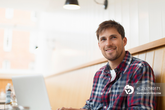 Smiling man working at laptop in cafe