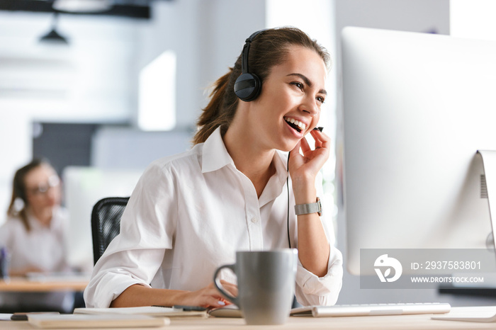 办公室呼叫中心里情绪激动的商务女性戴着耳机用电脑工作。