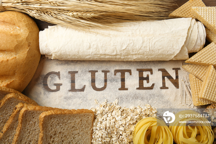 The word GLUTEN and flour products on wooden surface closeup