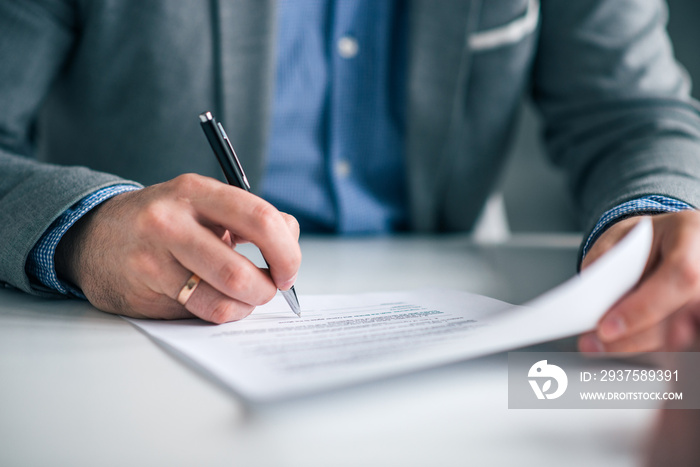 Businessman hand signing contract, close-up.