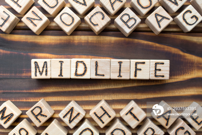 midlife wooden cubes with letters, middle age concept, around the cubes random letters, top view on 