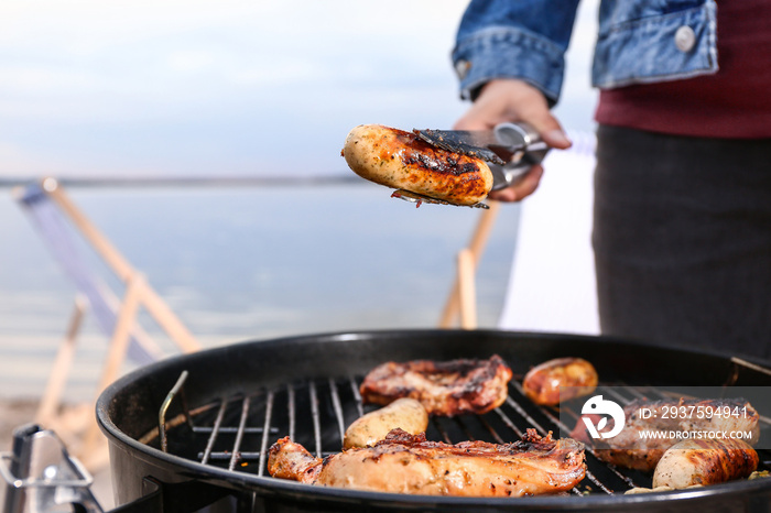 Man cooking meat on barbecue grill outdoors, closeup