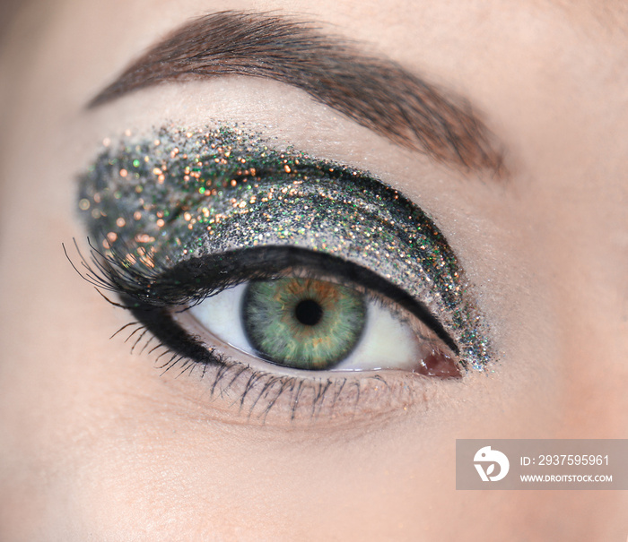 Female eye with fancy glitter makeup, closeup