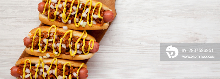 Homemade detroit style chili dog on a rustic wooden board on a white wooden background, top view. Fl