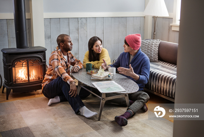 Friends gathering by coffee table and fireplace, sitting on carpet, talking