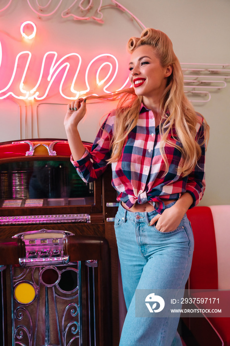 Photo of young joyful woman smiling while leaning jukebox