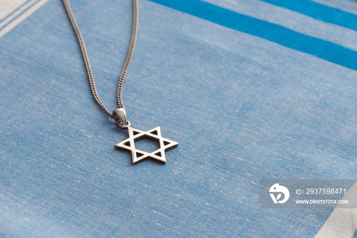 Star of David necklace, Magen David, on white-blue fabric.