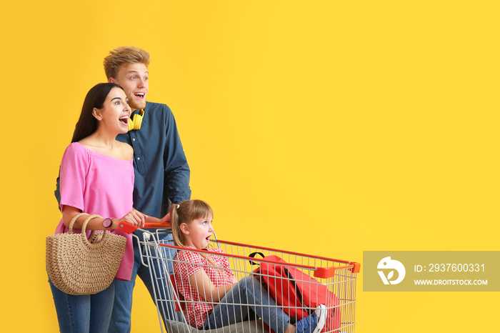 Family with shopping cart on color background