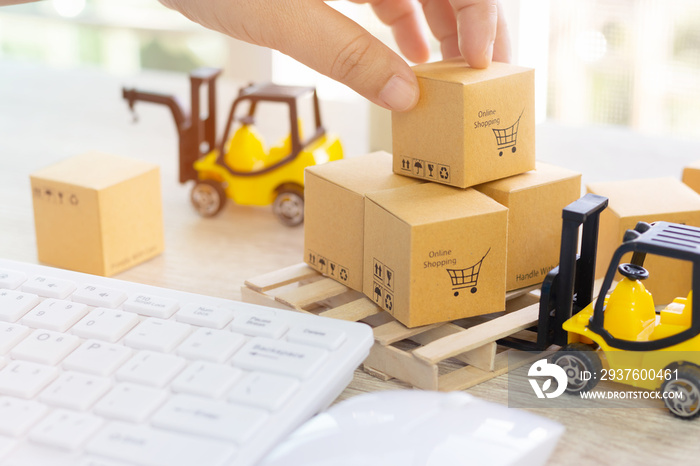 Mini forklift truck load cardboard boxes with symbols on wood pallet and fingers over its and keyboa