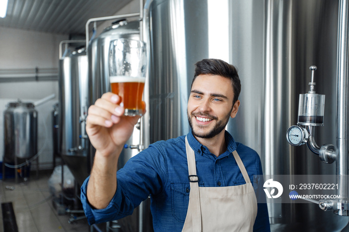 Professional brewery tasting beer in glass at manufacturing