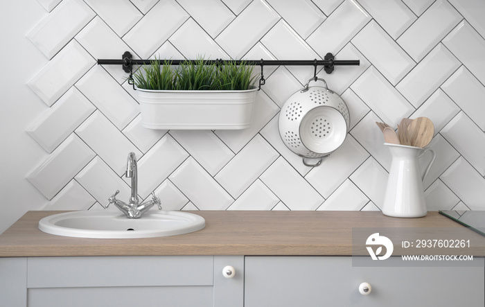 Wooden kitchen sink counter with plant pot and different wooden utensils