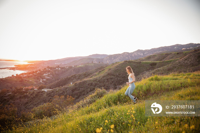 Side view of athlete exercising on mountain against clear sky during sunset