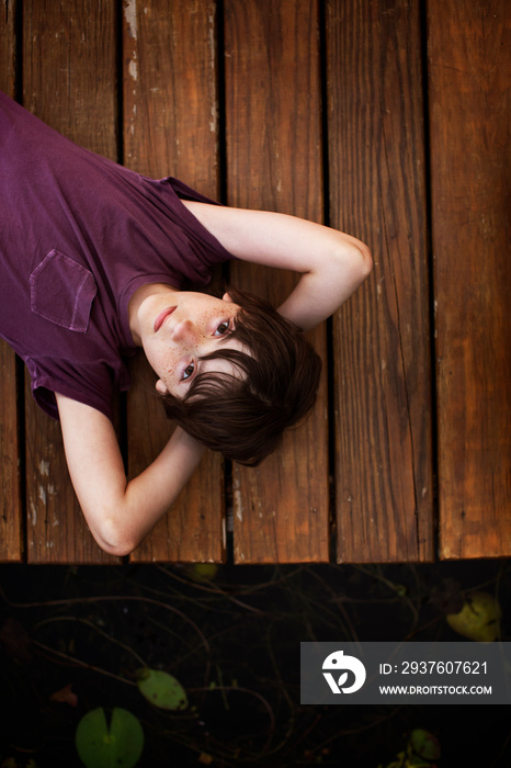 Overhead view of boy lying on jetty