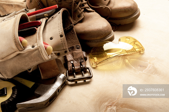 工具带黄色靴子护目镜蚂蚁工具在胶合板上的施工概念背景