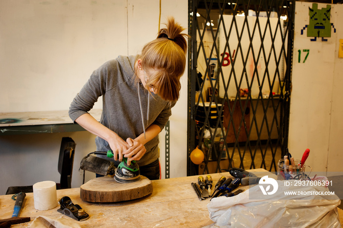 Young woman sanding wood