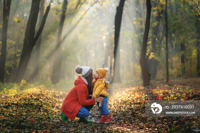 Mom kissing her little girl. Sunny day at autumn forest