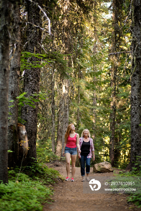 Mother with adult daughter walking in forest