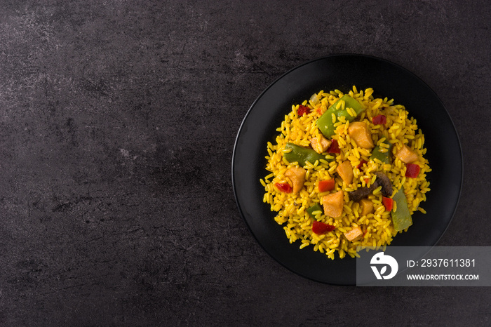 Fried rice with chicken and vegetables on black plate
