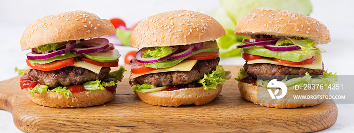 Big sandwich - hamburger burger with beef, avocado, tomato and red onions on light background. Ameri