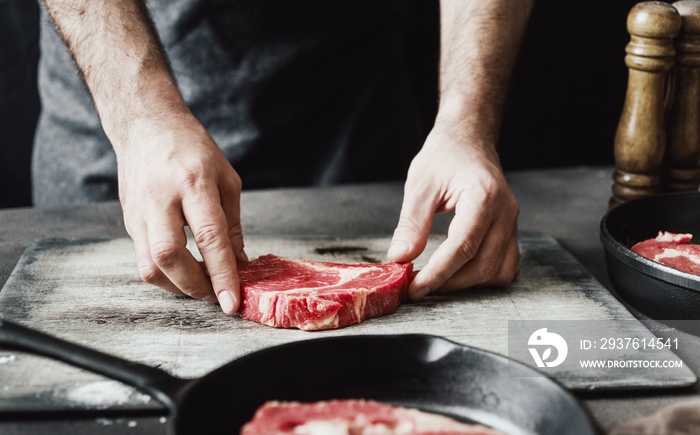 Man preparing beef steak on wooden table