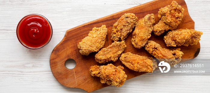 Chicken wings on a rustic wooden board with red pepper sauce on a white wooden background. Top view,