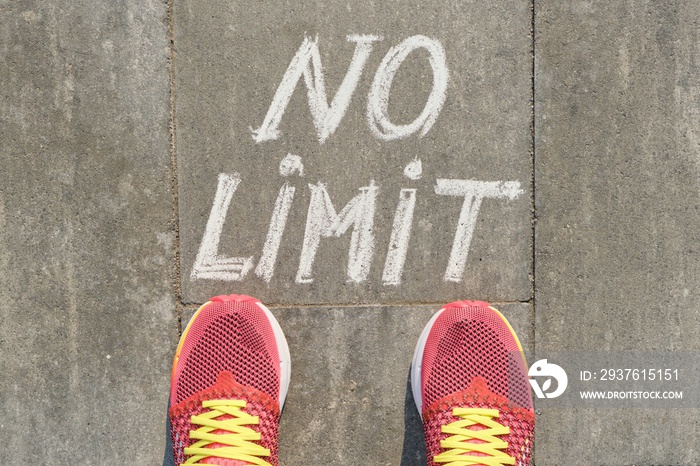 No limit text on gray sidewalk with woman legs in sneakers, top view