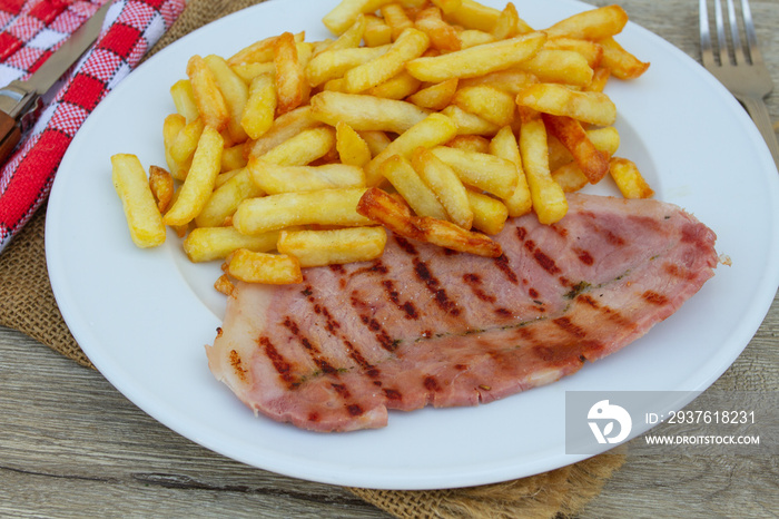 tranche de jambon grillé et frites dans une assiette