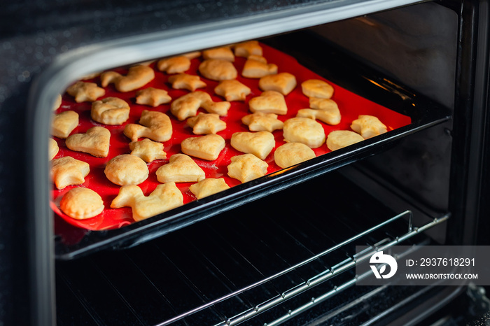 Sweet tasty delicious curd ginger cookies baking in hot oven stove on tray and red bright silicone b