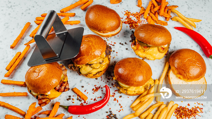 A closeup shot of tasty smash burgers, French fries, and red spicy peppers on the white background