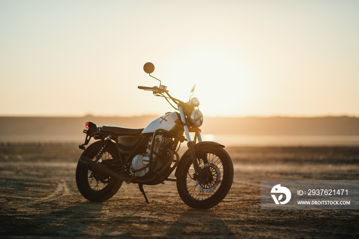 old custom beautiful cafe racer motorcycle in the desert at sunset or sunrise