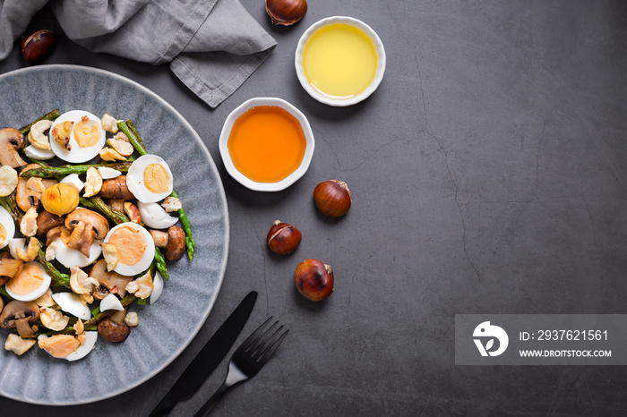 Salad with chestnuts, mushroom, asparagus and eggs on grey stone background, top view, autumn dish, 