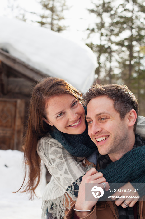 Portrait happy affectionate couple hugging outside snowy cabin