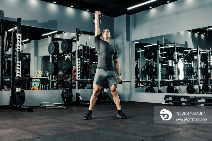 A strong man lifting weights with one arm in a gym. Functional exercises and healthy life concept.