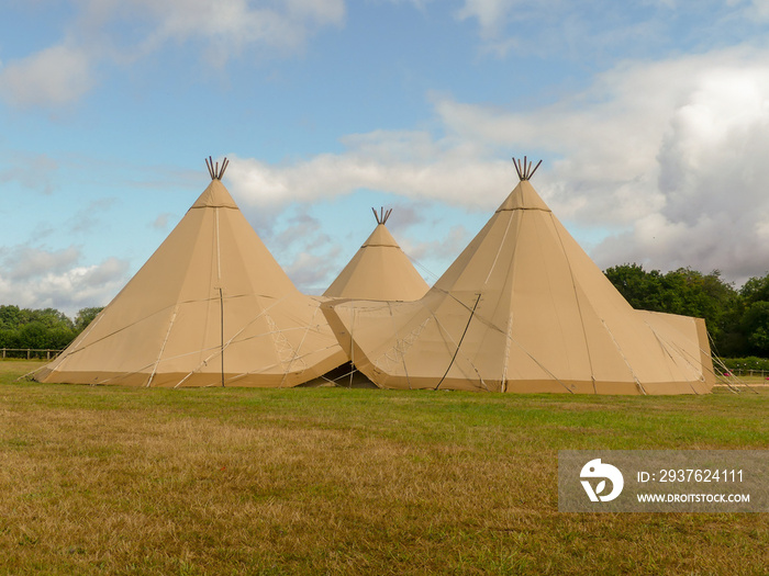 Three large tepees set up for a wedding event on farmland