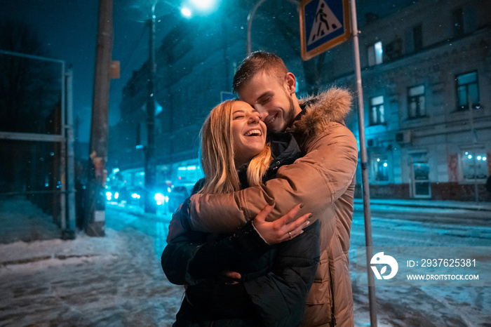 Young adult couple walking on snow covered sidewalk