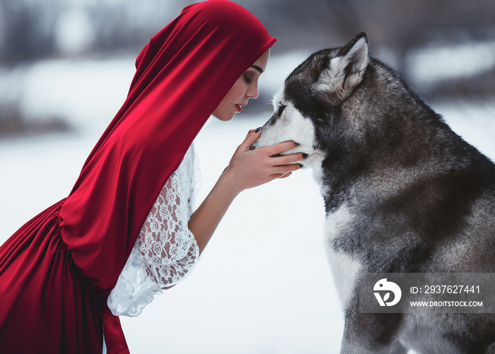 Girl in costume Little Red Riding Hood with dog malamute like a