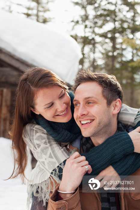 Happy affectionate couple hugging outside snowy cabin