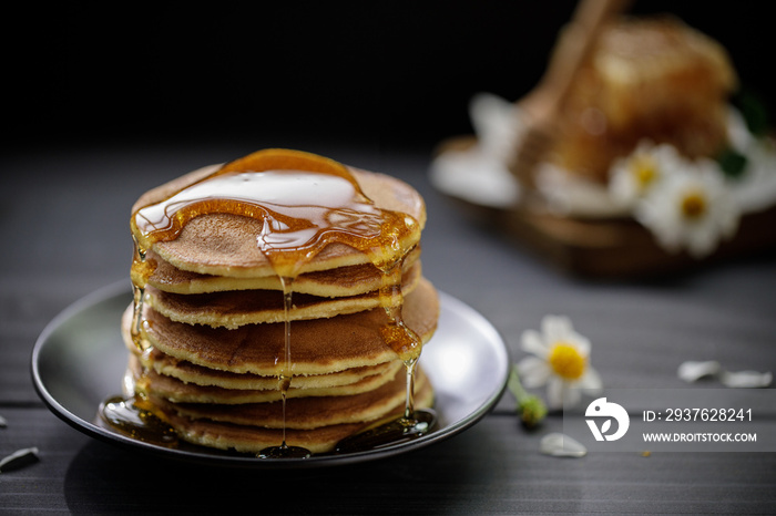 Honey dripping on the stack of pancakes for breakfast on the wooden table, healthy products by organ