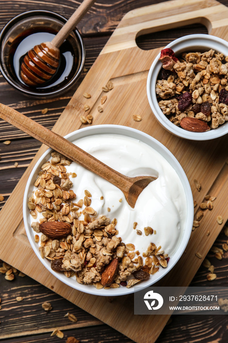 Bowl with tasty yogurt, oatmeal and almonds on wooden background