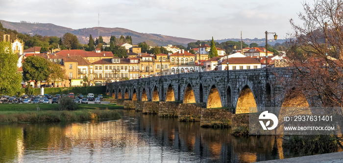 Roman bridge over the Lima river in the evening light, with the historic city of Ponte de Lima in th