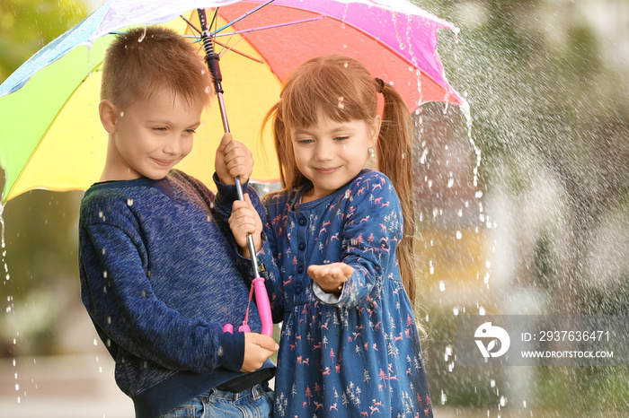 Portrait of cute children with umbrella in rain