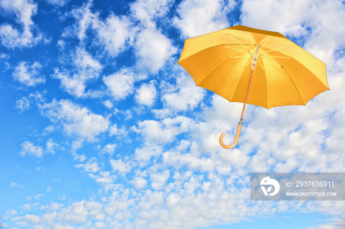 Yellow umbrella flies in sky against of white clouds.Wind of change concept.