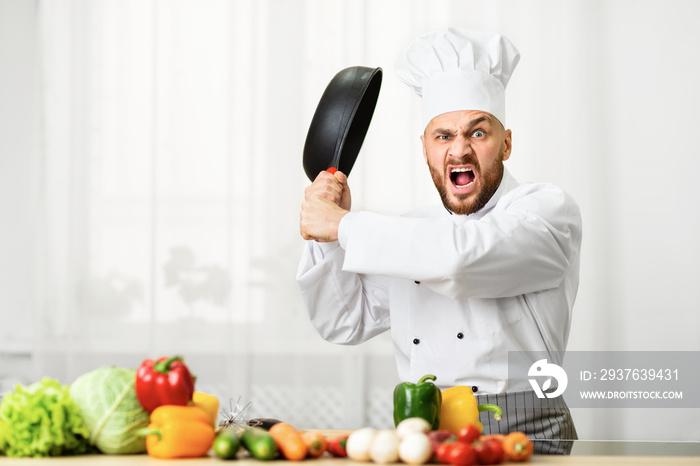 Angry Chef Man Raising Pan Threateningly Standing In Kitchen