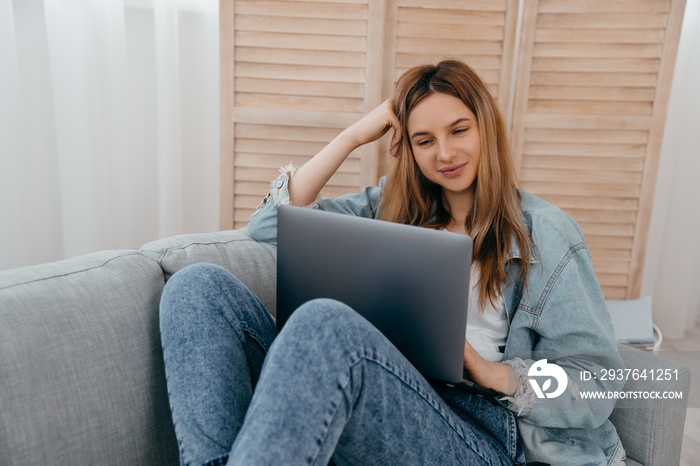 Smiling young teenage girl wear headphones video calling on laptop. Happy woman looking at computer 