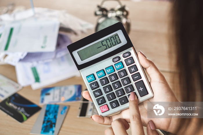 woman hand holding calculator showing number budget deficit for credit card debt payment with some b