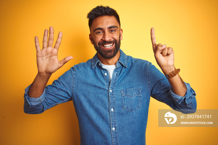 Young indian man wearing denim shirt standing over isolated yellow background showing and pointing u