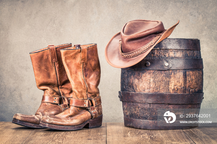 狂野西部复古牛仔皮靴，帽子和橡木桶。复古风格的过滤照片