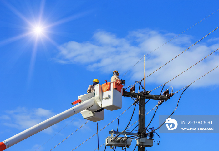 Electricians  repairing wire of the power line on bucket  hydraulic lifting platform vehicle on blue