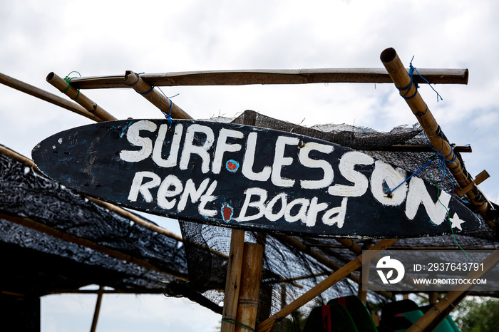 The inscription  Surf lesson  on black surfboard. Advertising on the beach.