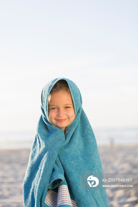 Portrait cute girl wrapped in towel on sunny beach